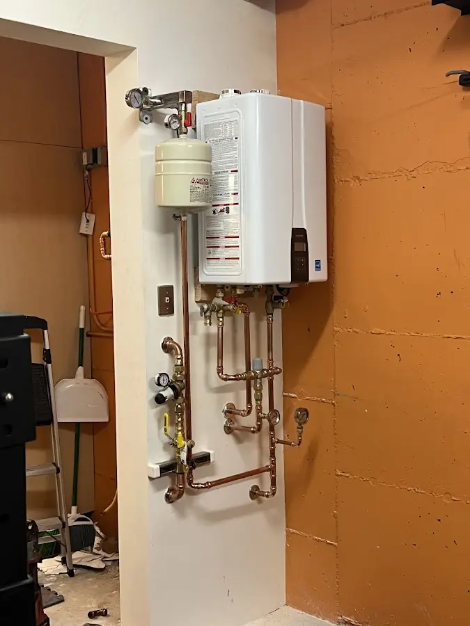 Plumbing technician inspecting water heater connections in Waldoboro